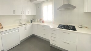 Uma cozinha moderna com armários brancos, fogão a gás e lava-louças.