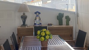 Uma varanda com mesa, cadeiras, um abajur, uma figura decorativa e cactos.
