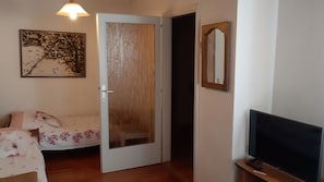 Una habitación con cama, televisión, puerta y un cuadro en la pared.