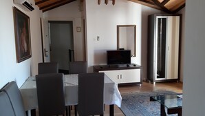 A dining area with a table and chairs, a television on a cabinet, and a mirror on the wall.