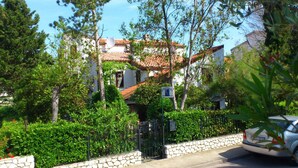 A residential area with a stone wall, a gated entrance, and a parked car.