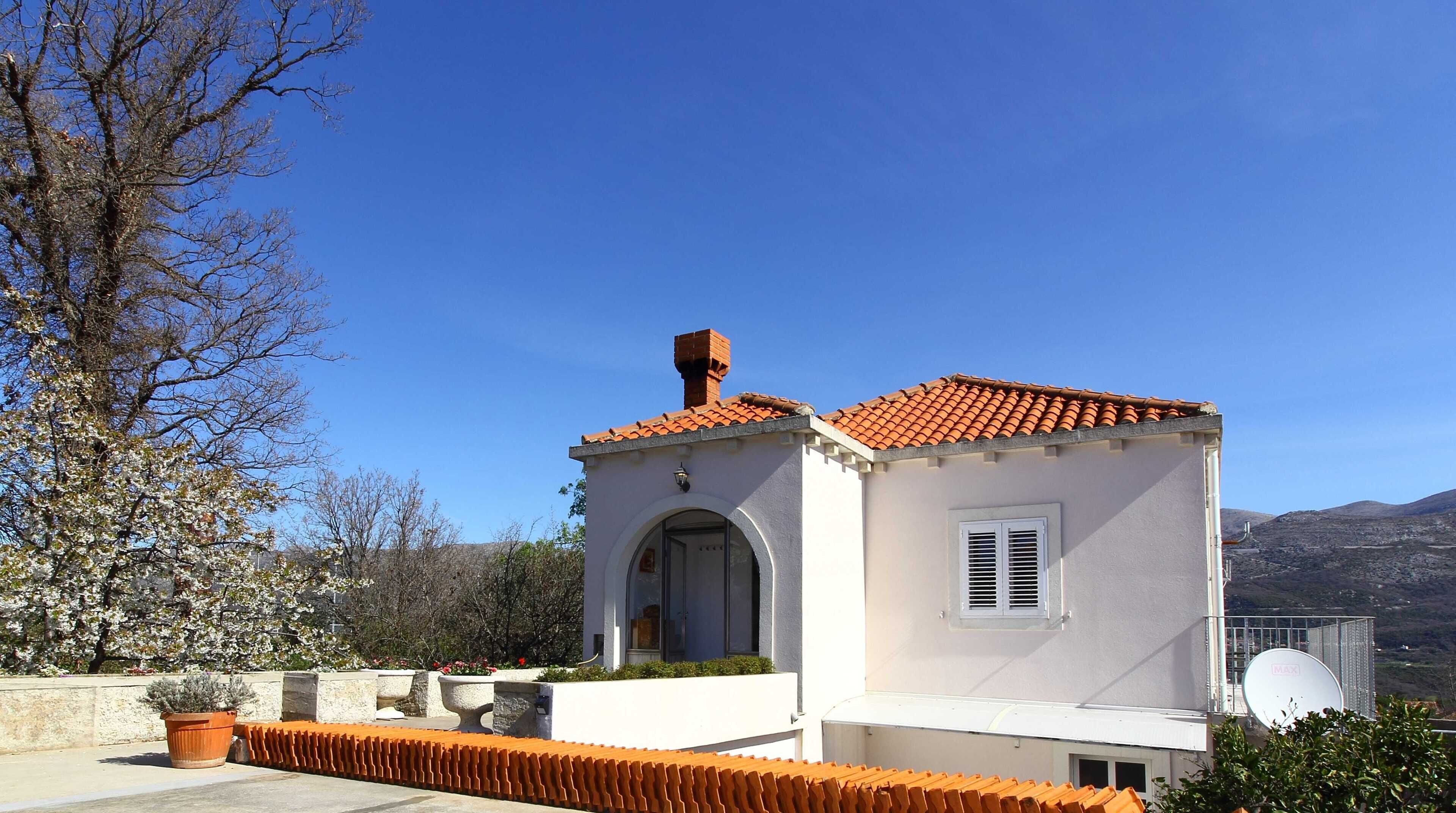 A small building with a tiled roof, a chimney, and a door with a window.
