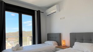 Une chambre d’hôtel avec deux lits, un balcon et la climatisation.