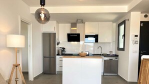 Une cuisine moderne avec des armoires blanches, des appareils en acier inoxydable et un îlot central.
