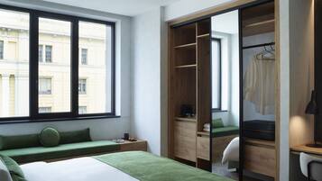 Ein modernes Hotelzimmer mit einem großen Bett, einem grünen Sofa, einem Holzschrank und einem Schreibtisch mit Stuhl.