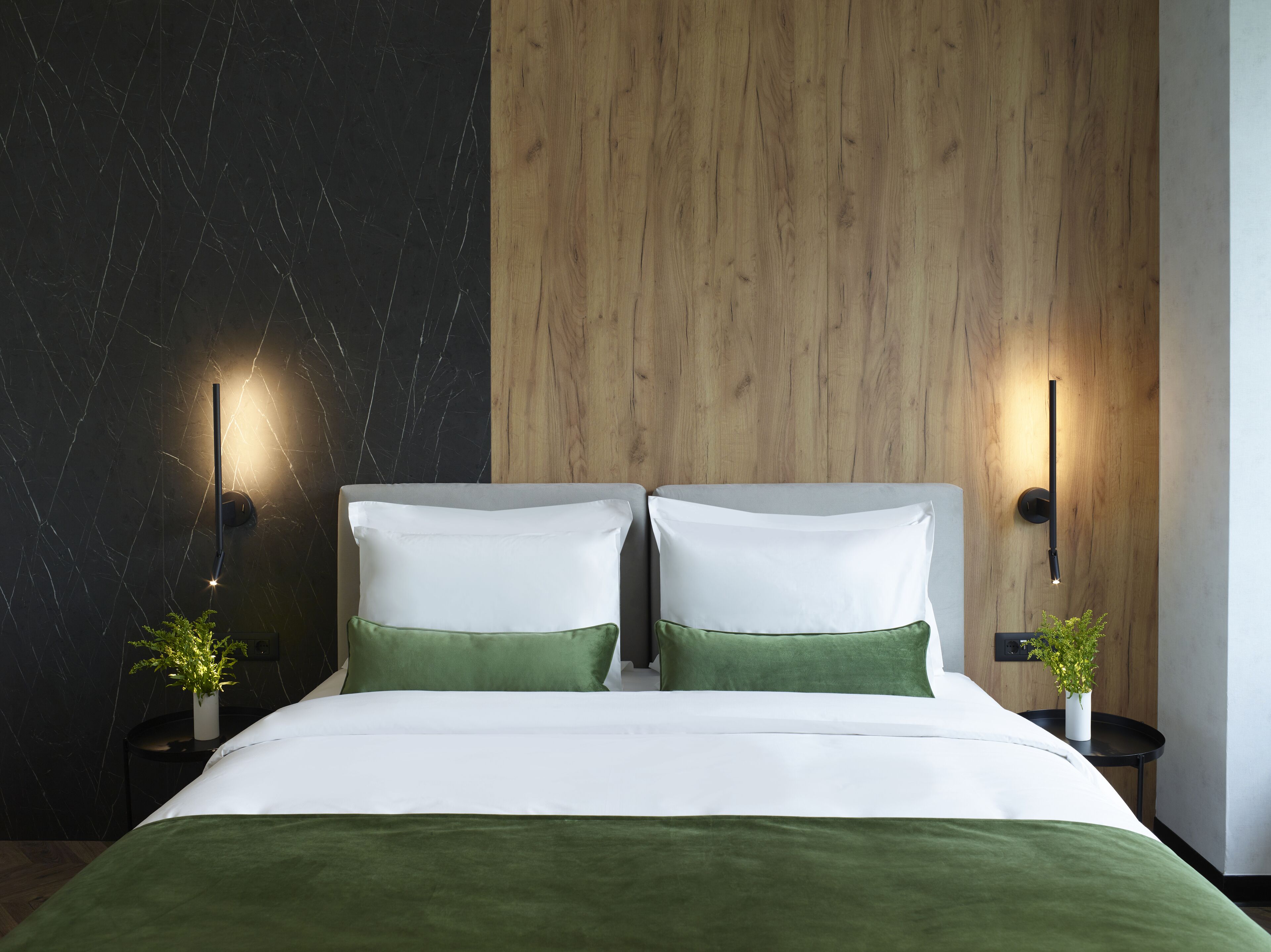 Un dormitorio moderno con un diseño de pared dividida, que presenta una sección de mármol negro y un panel de madera.