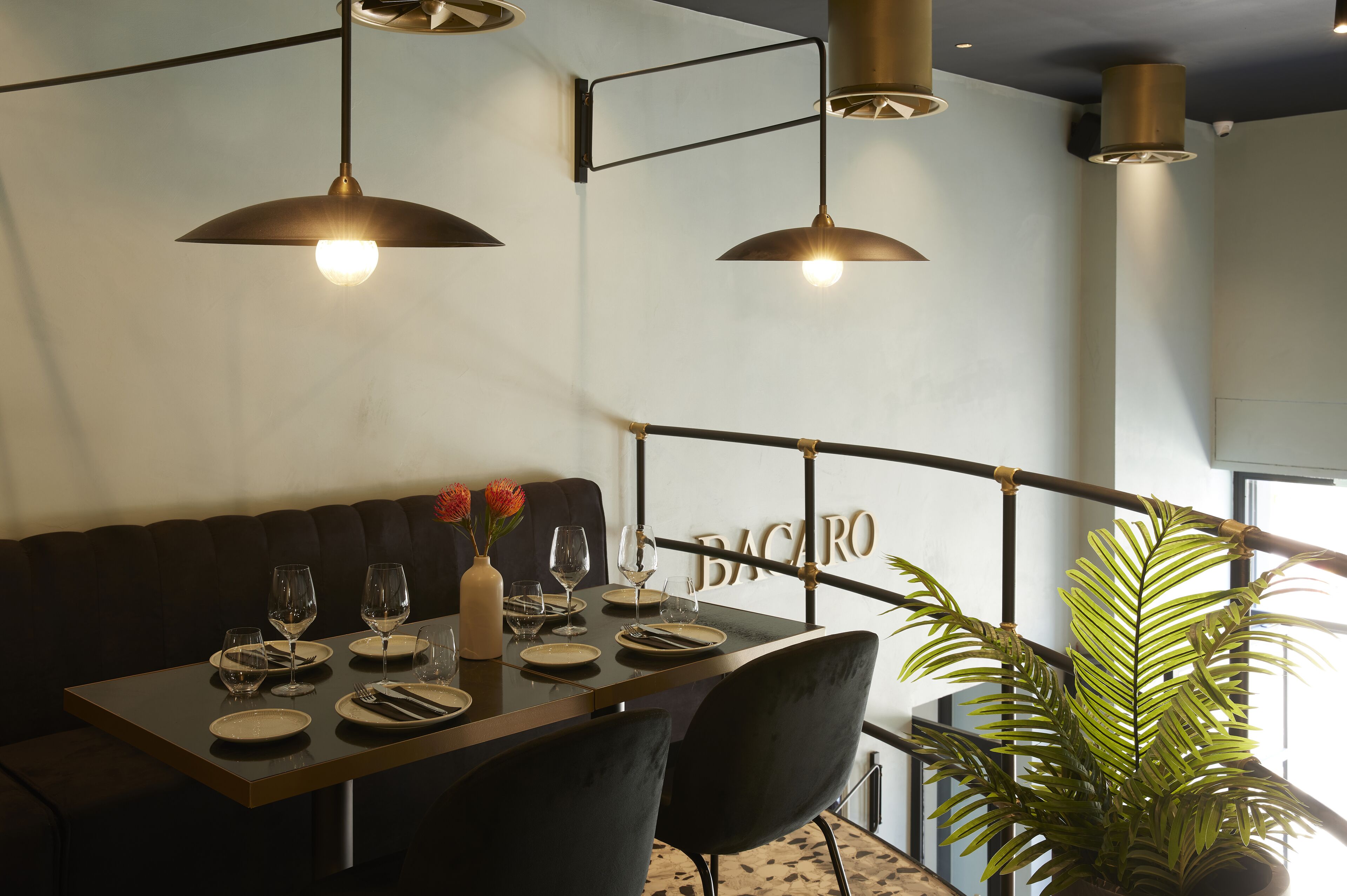 A dining area with a table set for four, black chairs, and pendant lighting.