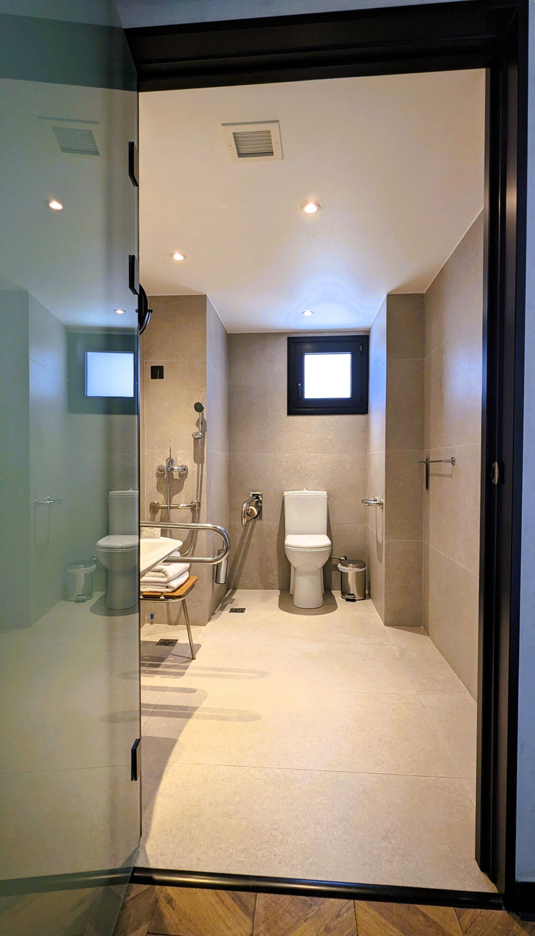 twin room customized for mobility needs | bathroom | rainfall showerhead, designer toiletries, hair dryer, slippers