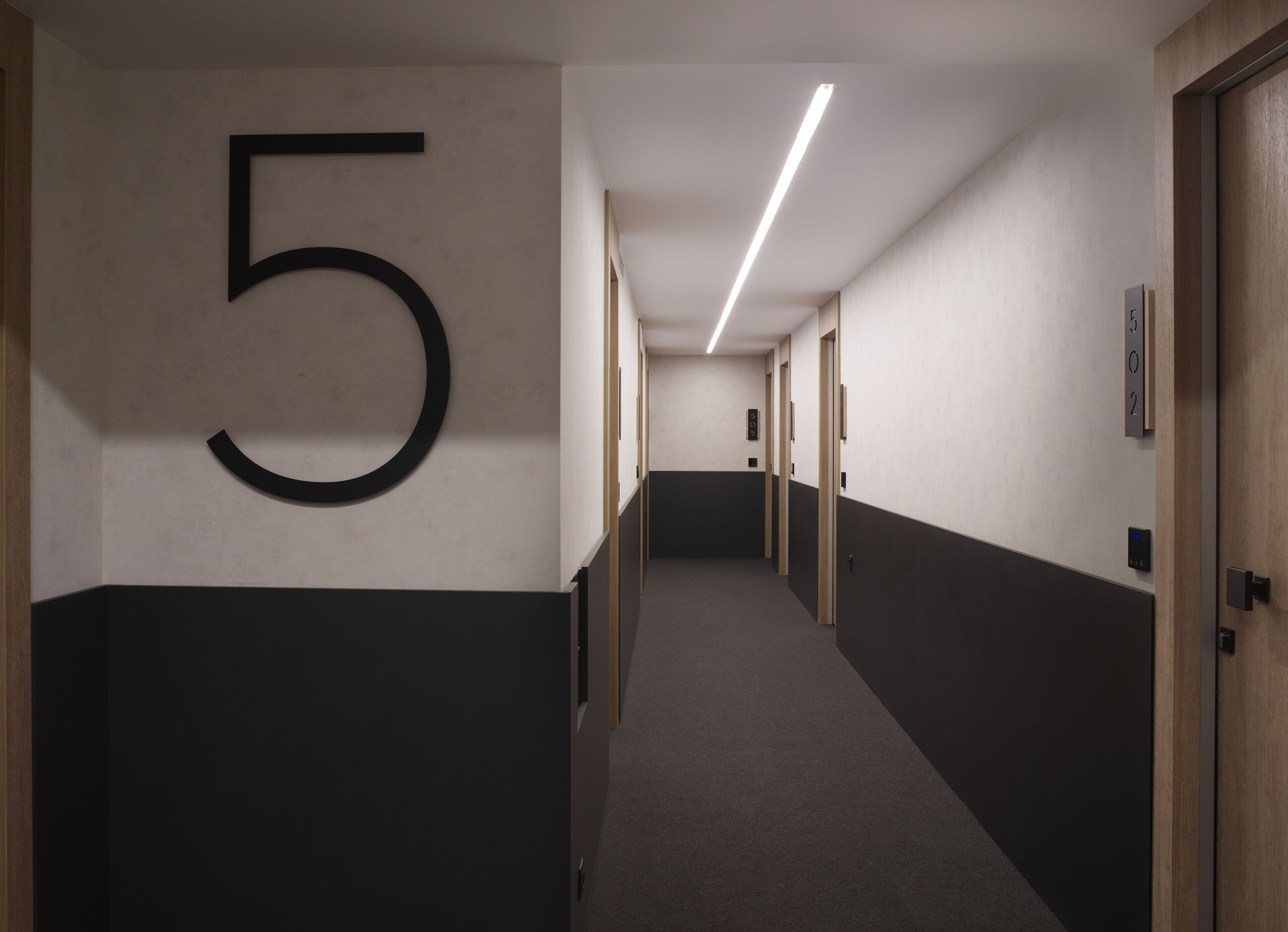 A hallway with a number '5' on the wall, doors, and a light fixture.
