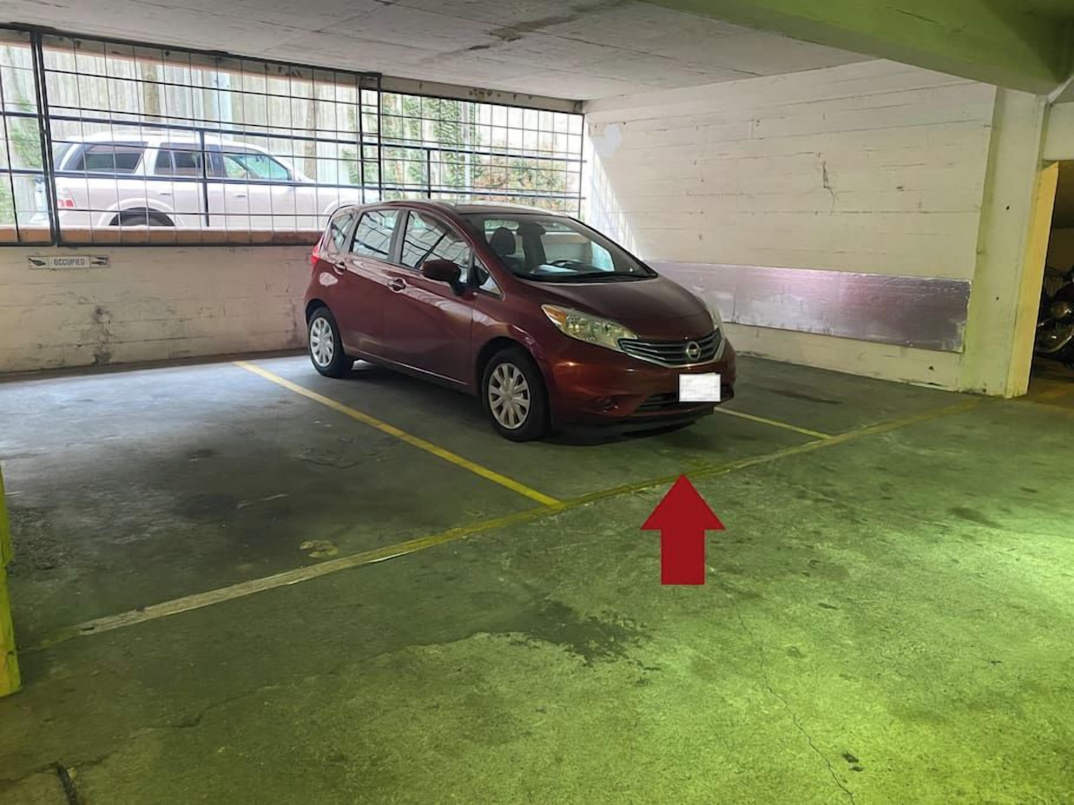 Ett parkeringsgarage med en röd bil parkerad på en anvisad plats.