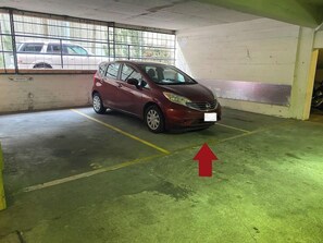 A parking garage with a red car parked in a designated space.