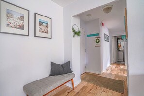 Un pasillo con un banco, cuadros en la pared y una puerta que da a otra habitación.