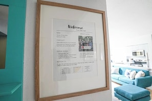 Un panneau d’accueil encadré, indiquant les coordonnées, les règles de la maison et une section pour les commentaires.