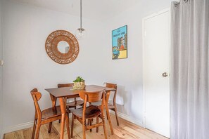 A dining area with a wooden table and chairs, a woven wall hanging, and a framed picture on the wall. - Tranquil 2BR downtown condo, Parking, King bed (Seattle)