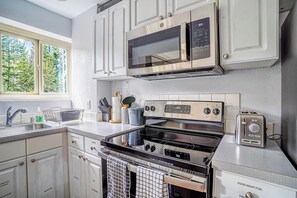 Una cocina moderna con electrodomésticos de acero inoxidable, muebles blancos y un ventanal que proporciona luz natural.