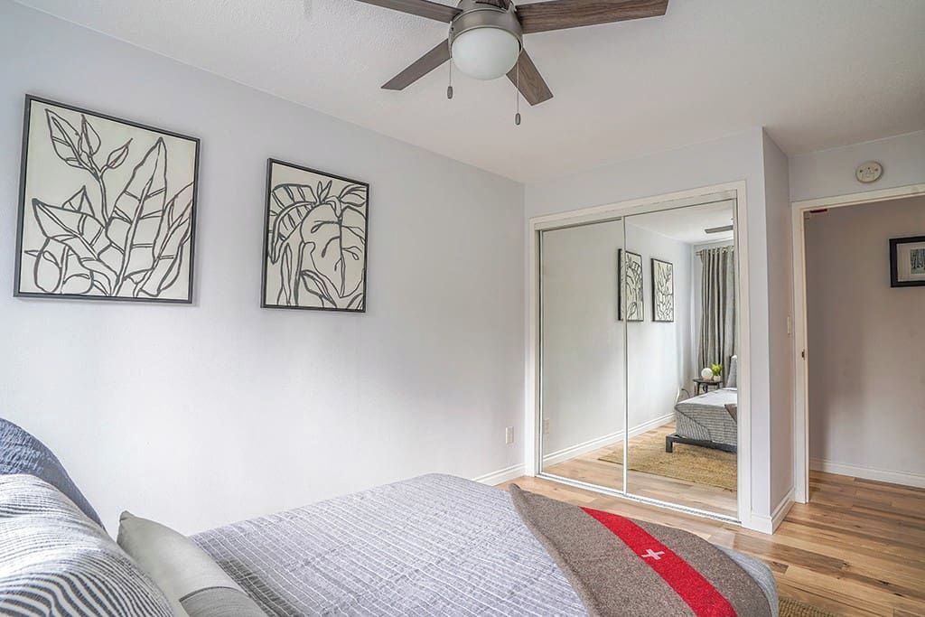 A bedroom with a bed, a ceiling fan, and two framed wall art pieces.