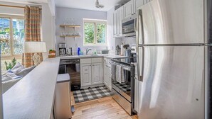 Una cocina moderna con electrodomésticos de acero inoxidable, lavavajillas y un ventanal que proporciona luz natural.
