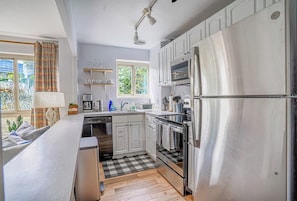 A modern kitchen with stainless steel appliances, a dishwasher, and a window providing natural light.