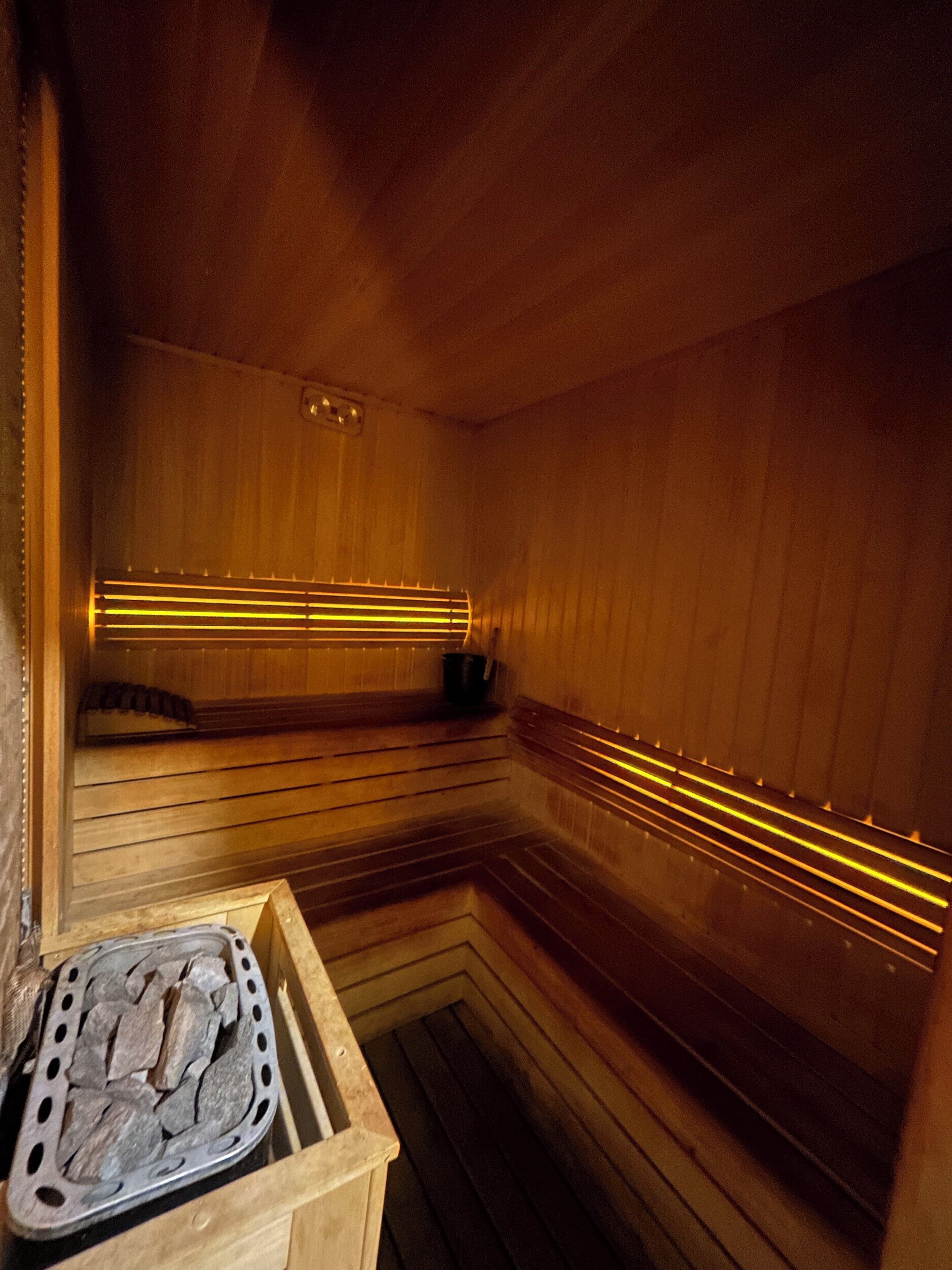 Una sauna con bancos de madera y una bandeja de piedra.
