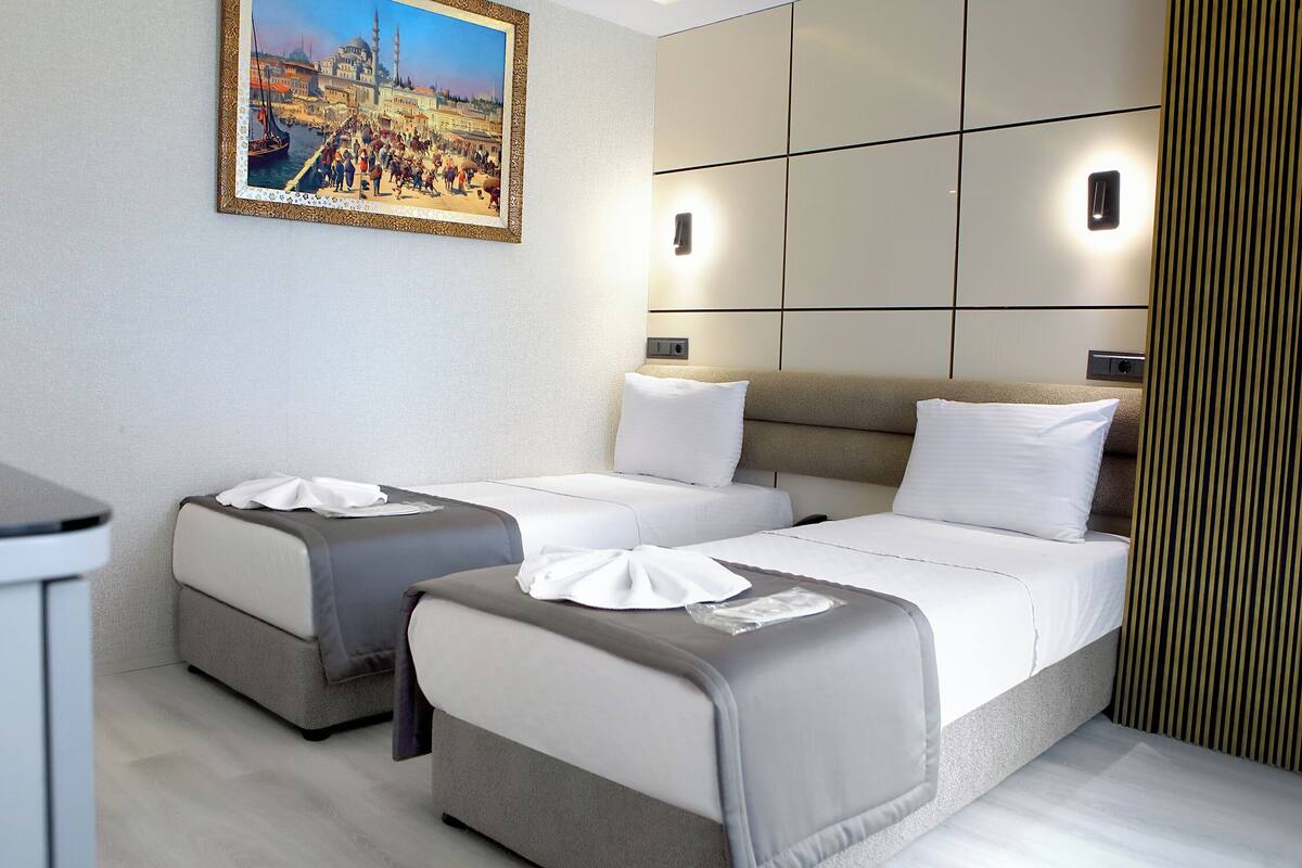 A hotel room with two beds, a painting of a cityscape, and a modern design.