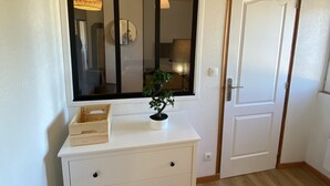 A white dresser with drawers, a small potted plant, and a window with a black frame.