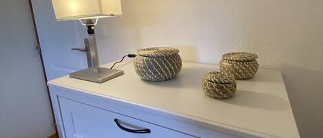 En vit byrå med tre lådor och en lampa ovanpå. Ovanför byrån hänger två inramade bilder med djurmotiv.