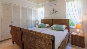 A bedroom with a large bed, two bedside tables, and a ceiling fan. - The Falls Villa No. 1 | Elegant Caribbean Retreat in Holetown (Holetown)