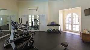 A gym with exercise equipment, a mirror, and a door leading to another room. - The Falls Villa No. 1 | Elegant Caribbean Retreat in Holetown (Holetown)