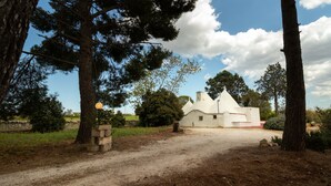 A rustic white building with a conical roof, surrounded by trees and a gravel path. - Holiday Home 'Trulli da Rosy' with Private Garden & Terrace (Martina Franca)