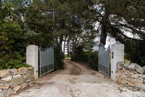 Une entrée fermée par un portail, avec des murs en pierre et un portail en métal.