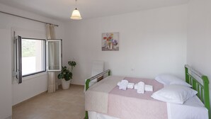 Une chambre à coucher avec un lit, une fenêtre, une plante et un tableau accroché au mur.