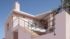 Un bâtiment rose avec un escalier menant à un balcon.