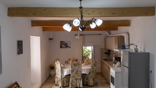 Un grand espace de vie comprenant un coin repas avec une table et des chaises, ainsi qu’une cuisine équipée d’un réfrigérateur.