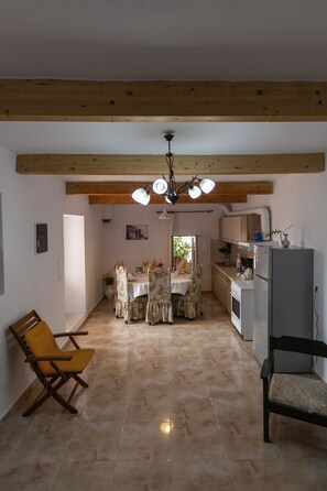 A spacious living area with a dining table, chairs, and a kitchen area with a refrigerator. - Kentrochori Mountain View House (Κεντροχώρι)