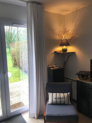 Enjoy a peaceful retreat with a garden view from this serene room, featuring a single bed, bedside table, and a dresser.
