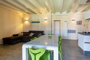 Uma sala de estar moderna com um sofá seccional, uma mesa de jantar com cadeiras e uma área de cozinha com fogão.