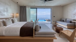 Ein modernes Schlafzimmer mit einem Bett, einer Couch und Blick auf den Ozean.