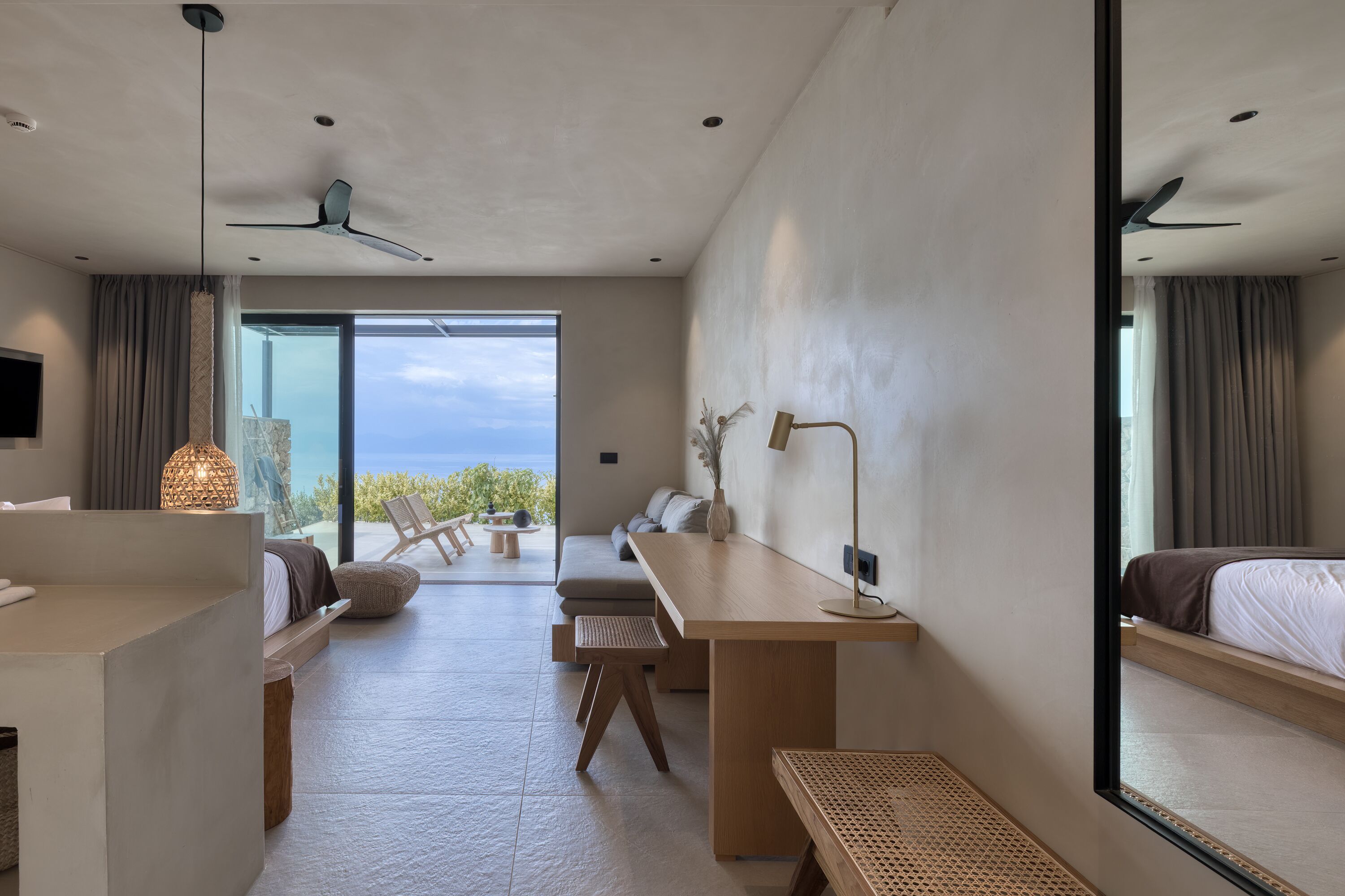 Una habitación de hotel moderna con una cama grande, un escritorio, un sofá y vistas al océano.