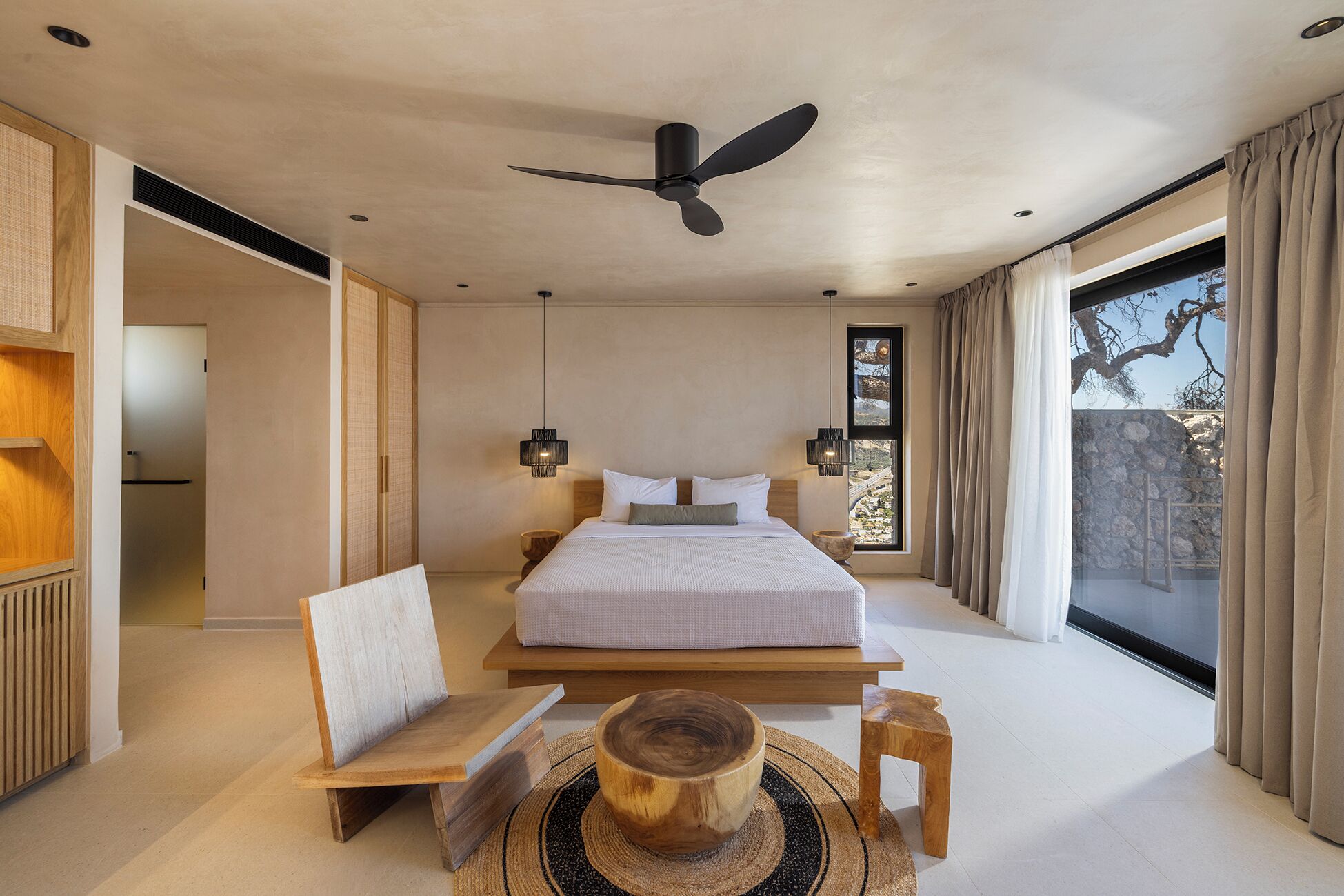 Un dormitorio moderno con una cama grande, ventilador de techo y vistas al exterior.