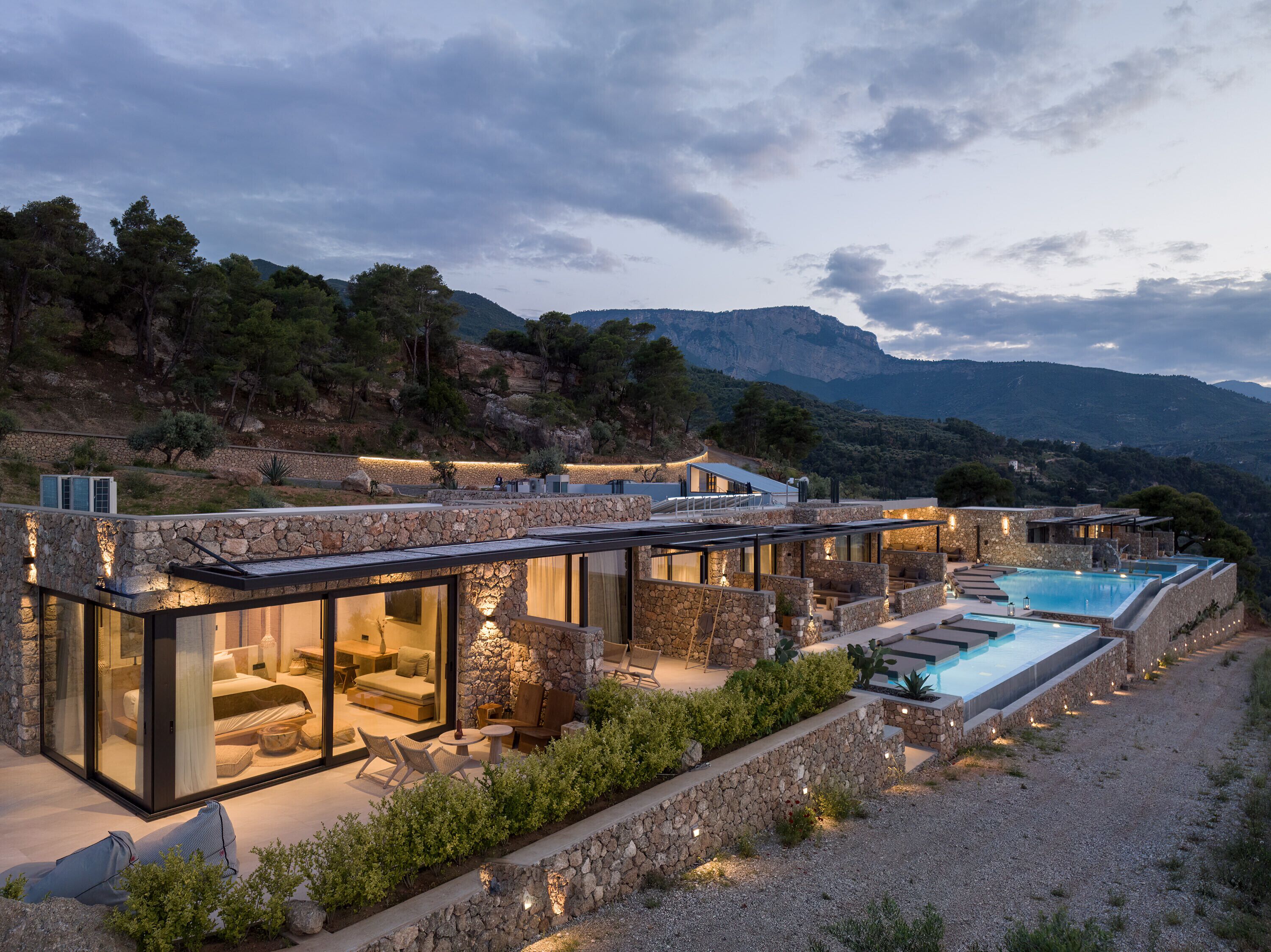 A modern villa with a pool, stone walls, and glass enclosures.