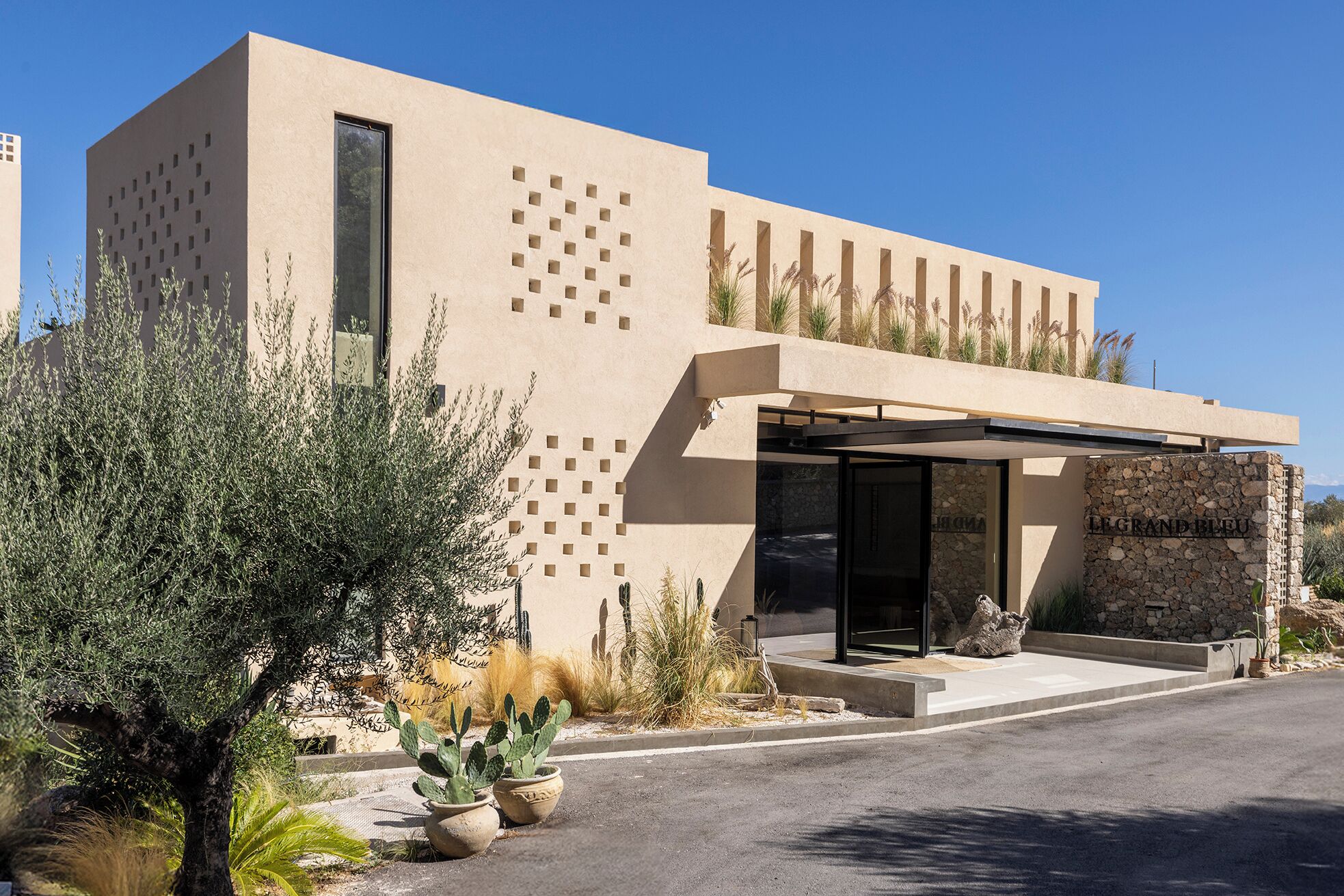 A modern building with a flat roof, a covered entrance, and a stone facade.