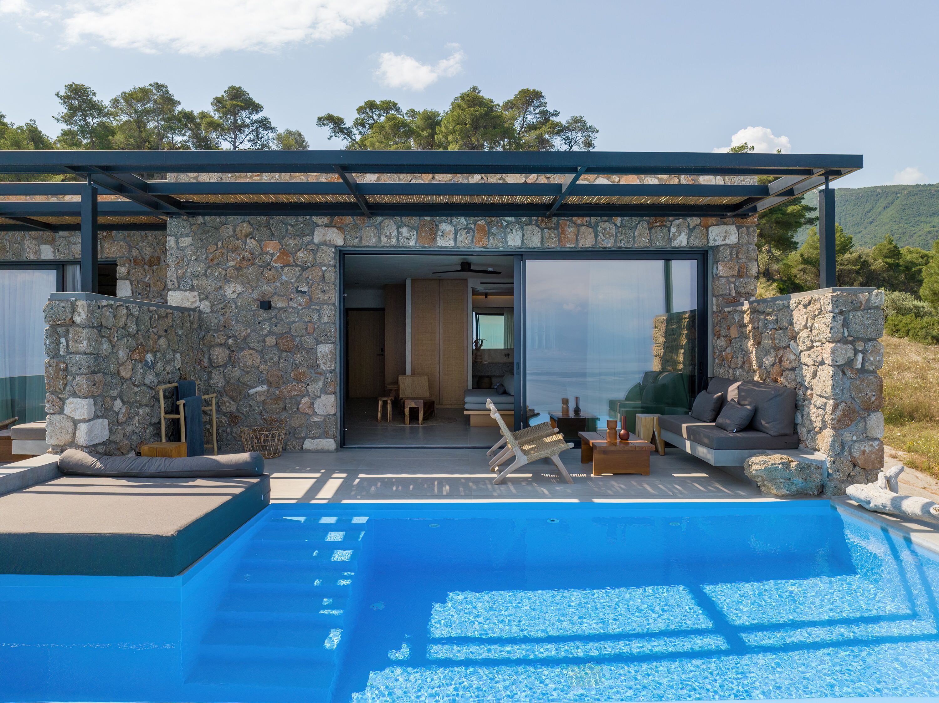 A modern outdoor pool area with stone walls and a covered seating area.