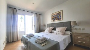 A hotel room with a bed, two bedside tables, a nightstand, a painting, and a window with curtains. - Casa Can Alou, authentic Mallorquin house nestled in the village of Porto Colom (Felanitx)