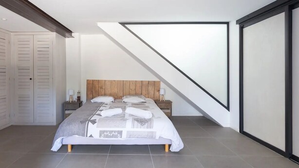 A modern bedroom with a sloped ceiling, a wooden headboard, a bed with a patterned bedspread, a nightstand, and a wardrobe. - A 10 mn walk from the beach with view on the cap canaille house of 100 m2 (CASSIS)