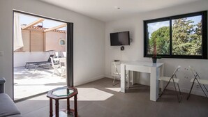 A modern room with a sliding glass door leading to an outdoor area, a white desk with a flat-screen TV, and a large window with a view of trees. - A 10 mn walk from the beach with view on the cap canaille house of 100 m2 (CASSIS)