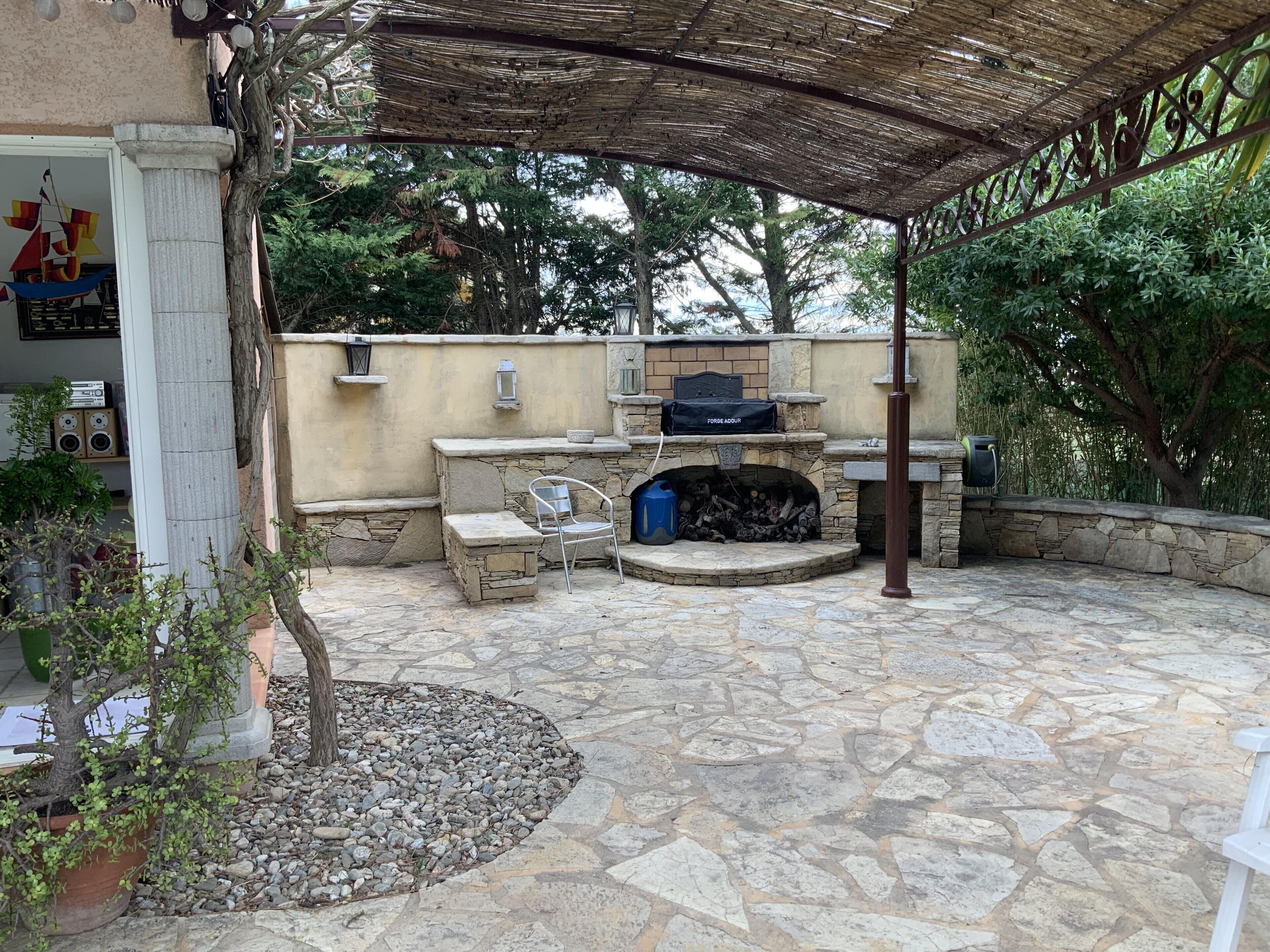 Eine Terrasse im Freien mit Kamin, Sitzgelegenheiten und Grill.