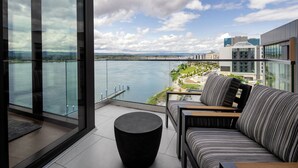 A balcony with a view of a body of water and distant buildings.