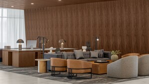 A modern living room with a wooden accent wall, a sofa set, a coffee table, and a desk area with a computer and lamps.