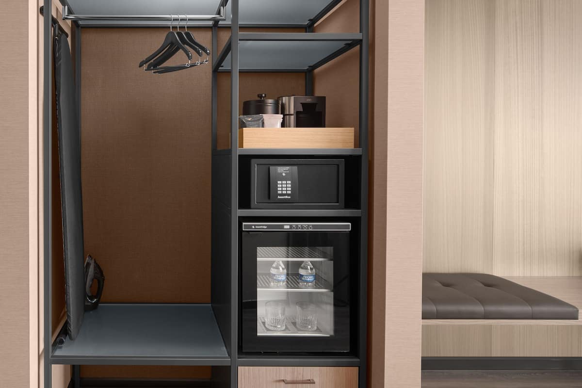 A compact storage unit with a microwave, a refrigerator, and a small seating area.