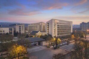 A multi-story hotel with a modern architectural design, featuring a prominent entrance and a parking area. - Garrya Xi'an Lintong (Xi'an)